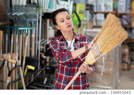 Adult woman choosing broom in household store Adult woman choosing broom in household store 136931043