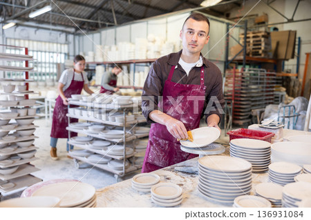 Young man cleaning blanks of ceramic products 136931084