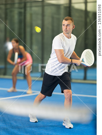 Young woman and man playing doubles tennis Young woman and man playing doubles tennis 136931098