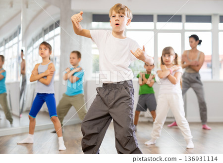 Group of preteen girls and boys enjoying active dance movement in studio Group of preteen girls and boys enjoying active dance movement in studio 136931114