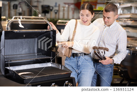 In store, married couple inspect mobile grill, buys barbecue device In store, married couple inspect mobile grill, buys barbecue device 136931124