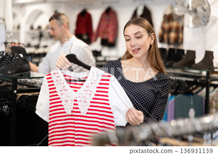 Young woman choosing blouse in clothing store Young woman choosing blouse in clothing store 136931139