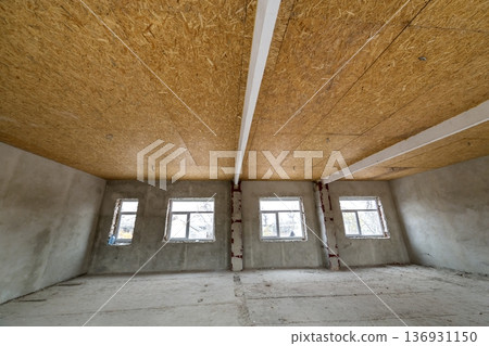 Unfinished apartment or house big loft room under reconstruction. Plywood ceiling, plastered walls, window openings, cement floor. Construction and renovation concept. Unfinished apartment or house big loft room under reconstruction. Plywood ceiling, plastered walls, window openings, cement floor. Construction and renovation concept. 136931150