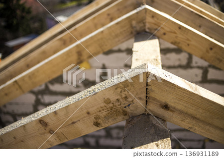 Close-up detail of roof frame of rough wooden lumber beams on background of misty mountain landscape in ecological area. Building, roofing, construction and renovation concept. Close-up detail of roof frame of rough wooden lumber beams on background of misty mountain landscape in ecological area. Building, roofing, construction and renovation concept. 136931189