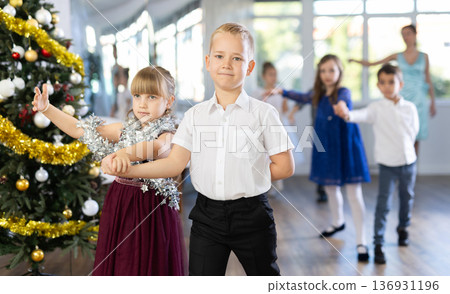Preteen children in elegant outfits practicing partner dance in Christmas studio Preteen children in elegant outfits practicing partner dance in Christmas studio 136931196
