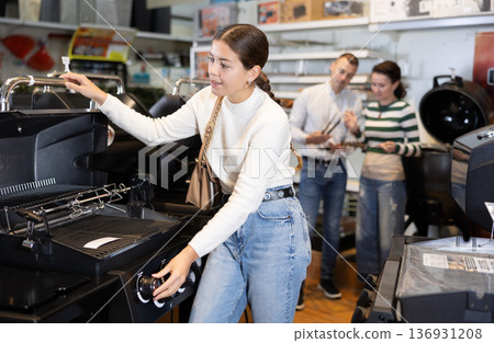 Young woman choosing BBQ grill in store Young woman choosing BBQ grill in store 136931208