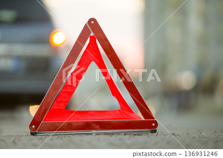 Red emergency triangle stop sign and broken car on a city street. Red emergency triangle stop sign and broken car on a city street. 136931246