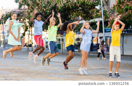 Cheerful tween girls and boys jumping together on summer city street Cheerful tween girls and boys jumping together on summer city street 136931256
