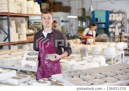 Potter explaining technique of crafting ceramic tableware in slipcasting molds Potter explaining technique of crafting ceramic tableware in slipcasting molds 136931258