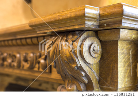 Close-up detail of carved wooden decorative piece of furniture with floral ornament made of natural hardwood. Art craft and design concept. Close-up detail of carved wooden decorative piece of furniture with floral ornament made of natural hardwood. Art craft and design concept. 136931281
