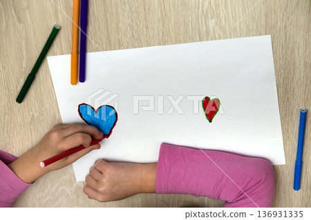 Child girl hands drawing with colorful pencils crayons heart on white paper. Art education, creativity concept. 136931335