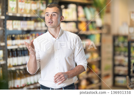 Interested young man walking through organic store aisle Interested young man walking through organic store aisle 136931338
