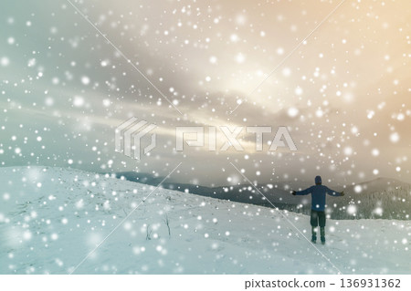 Back view of tourist hiker in warm clothing with backpack standing with raised arms on clearing covered with snow on spruce forest mountain and cloudy sky copy space background. Back view of tourist hiker in warm clothing with backpack standing with raised arms on clearing covered with snow on spruce forest mountain and cloudy sky copy space background. 136931362