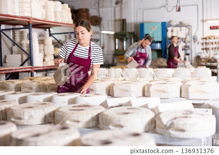 Female ceramicist filling casting molds with slip in pottery workshop 136931376