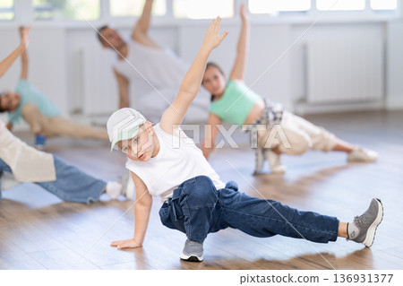 Preteen boys and girls studying movement of contemporary dance in classroom with his friends Preteen boys and girls studying movement of contemporary dance in classroom with his friends 136931377