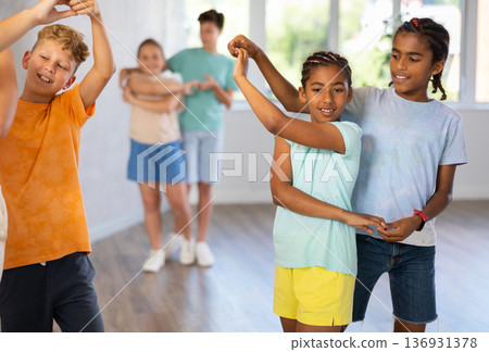 Active preteen children practicing Ballroom dances in pairs in training hall 136931378