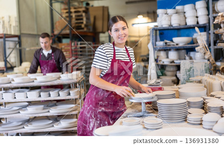 Female ceramicist using sponge to clean pottery plates in workshop Female ceramicist using sponge to clean pottery plates in workshop 136931380