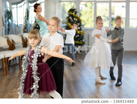 Preteen children in elegant outfits practicing partner dance in Christmas studio 136931489