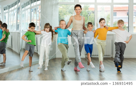 Smiling preteen children learning to dancing folk dance in row in studio Smiling preteen children learning to dancing folk dance in row in studio 136931495