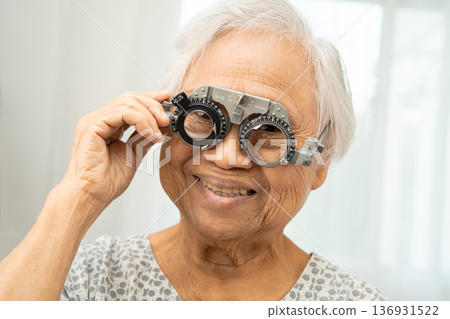 Asian senior woman wearing ophthalmic vision eye test and using optical trial frame. Asian senior woman wearing ophthalmic vision eye test and using optical trial frame. 136931522