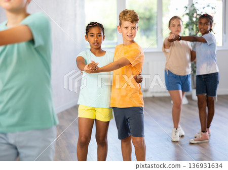 Light-skinned boy and African girlie learn figures of pair jive dance and train before competition Light-skinned boy and African girlie learn figures of pair jive dance and train before competition 136931634