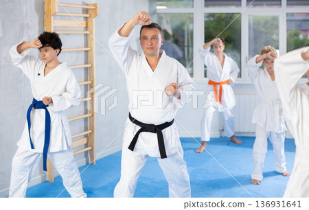 Karate master demonstrating hand strikes to teenagers during group kata Karate master demonstrating hand strikes to teenagers during group kata 136931641