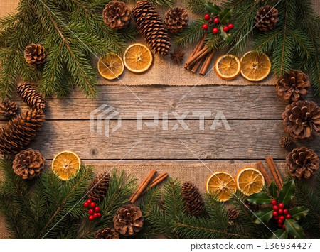Christmas rustic wooden background with frame of pine branches cones dried oranges and cinnamon 136934427