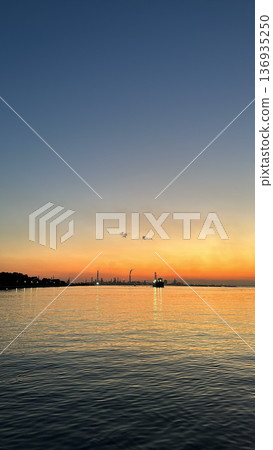 夕陽下波光粼粼的大海,以及遠處工廠的夜景 夕陽下波光粼粼的大海,以及遠處工廠的夜景 136935250