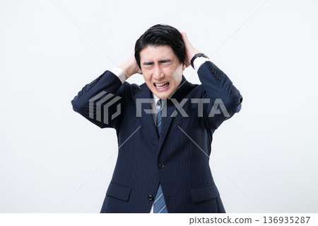 A businessman in a suit holding his head. Image of trouble, mistake, failure, etc. White background A businessman in a suit holding his head. Image of trouble, mistake, failure, etc. White background 136935287