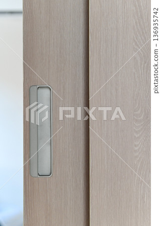 Light wood sliding door with recessed metal handle, modern minimalist style, close up detail showing texture and clean lines, suitable for contemporary home or office interior design Light wood sliding door with recessed metal handle, modern minimalist style, close up detail showing texture and clean lines, suitable for contemporary home or office interior design 136935742