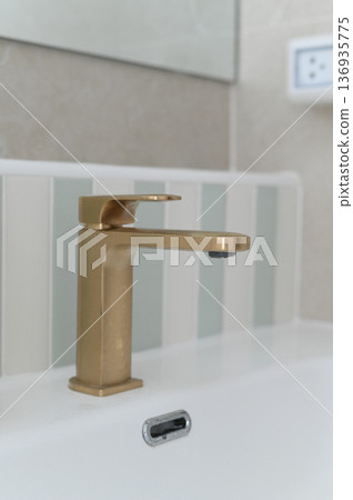 Modern gold faucet bathroom sink white ceramic minimalist style clean contemporary metal interior wall tile luxury elegant water tap hygiene home reflection vertical closeup plumbing design Modern gold faucet bathroom sink white ceramic minimalist style clean contemporary metal interior wall tile luxury elegant water tap hygiene home reflection vertical closeup plumbing design 136935775