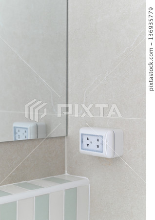 Electrical outlet wall bathroom mirror tile white modern clean safety interior design. Electrical outlet light colored tiled bathroom wall with mirror reflecting clean and modern interior design 136935779