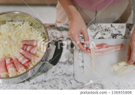 Enoki mushroom bacon cabbage hand kitchen preparation raw cooking marble countertop Enoki mushroom and bacon rolls being prepared by hand marble countertop with shredded cabbage metal bowl Enoki mushroom bacon cabbage hand kitchen preparation raw cooking marble countertop Enoki mushroom and bacon rolls being prepared by hand marble countertop with shredded cabbage metal bowl 136935806