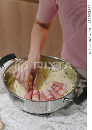 Woman hand preparing cabbage pork roll kitchen stainless pot marble countertop Preparing cabbage and pork rolls stainless pot marble countertop woman hand arranging ingredients home cooking cozy 136935833