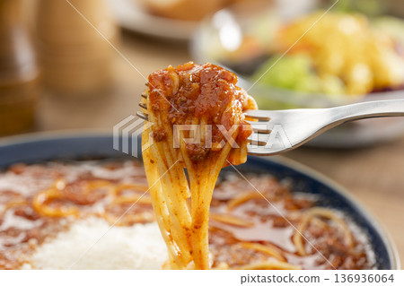 Close-up of a bowl of pasta in meat sauce soup being picked up with a fork just before eating Close-up of a bowl of pasta in meat sauce soup being picked up with a fork just before eating 136936064
