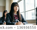 A female high school student in a blazer uniform is listening to a class with a serious look in her seat in the classroom 136936550