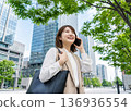 A smiling businesswoman talking on a smartphone in an office district in the city 136936554