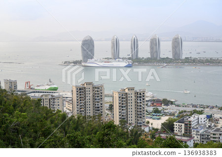 View of the sea bay, Phoenix Island with skyscrapers and a tourist ship in Sanya, Hainan, China View of the sea bay, Phoenix Island with skyscrapers and a tourist ship in Sanya, Hainan, China 136938383