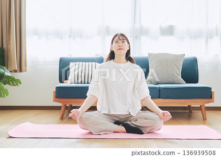 Mindfulness lifestyle of a woman in her 30s meditating and taking deep breaths at home Mindfulness lifestyle of a woman in her 30s meditating and taking deep breaths at home 136939508
