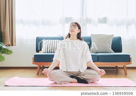 一位30多歲的女性在家中進行冥想和深呼吸，實踐正念生活方式。 136939509