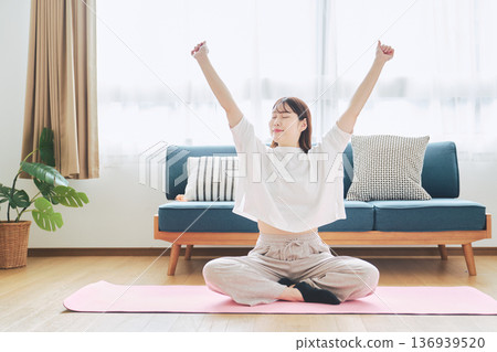Healthy habits of a woman in her 30s stretching at home Healthy habits of a woman in her 30s stretching at home 136939520
