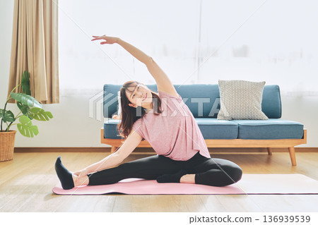一位30多歲的女性在客廳做瑜伽,展現她的健身生活 一位30多歲的女性在客廳做瑜伽,展現她的健身生活 136939539