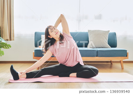一位30多歲的女性在客廳做瑜伽,展現她的健身生活 一位30多歲的女性在客廳做瑜伽,展現她的健身生活 136939540