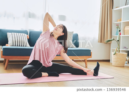 一位30多歲的女性在客廳做瑜伽,展現她的健身生活 一位30多歲的女性在客廳做瑜伽,展現她的健身生活 136939546