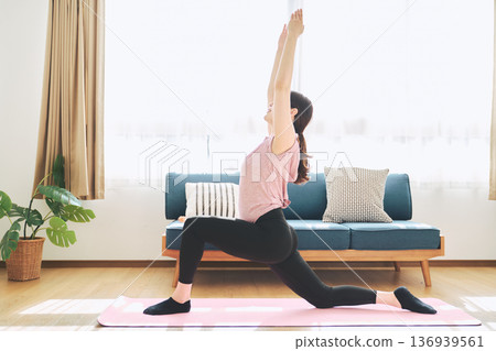 一位30多歲的女性在客廳做瑜伽，展現她的健身生活 136939561