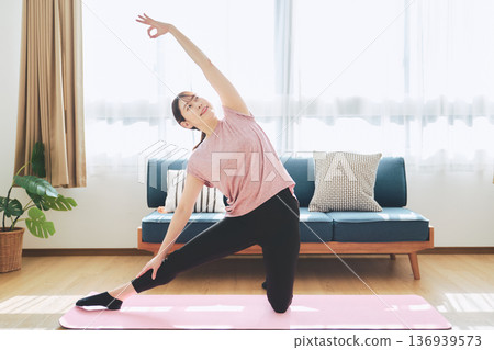 Fitness life of a woman in her 30s doing yoga poses in her living room 136939573