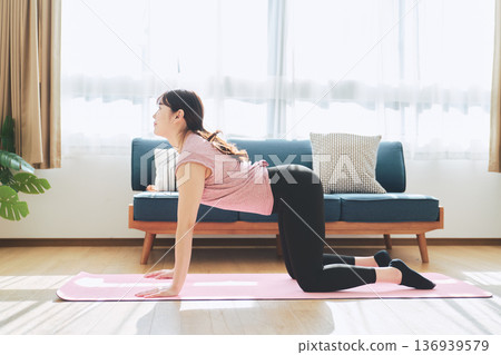 Fitness life of a woman in her 30s doing yoga poses in her living room 136939579