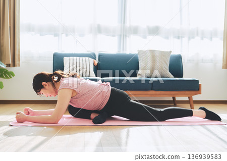 Fitness life of a woman in her 30s doing yoga poses in her living room 136939583