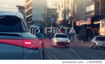 Rear side view of luxury car with turn on brake light. Speed light from taillight of car to right side. Clear traffic on the road with cars and blurred of town at Thailand. Rear side view of luxury car with turn on brake light. Speed light from taillight of car to right side. Clear traffic on the road with cars and blurred of town at Thailand. 136939902