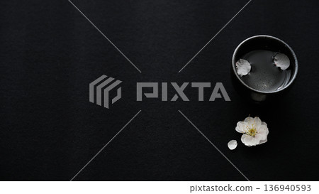 Plum blossoms and sake cups on a black background - Japanese spring design with space 136940593